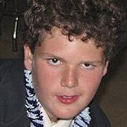 Image depicts Benjamin Barnhard - a Caucasian teenage boy with short curly brown hair facing the camera with a concentrated expression and half a smile.