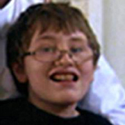 Image depicts Glen Freaney - a young Caucasian boy with short brown hair and glasses looking into the camera with a big open smile.