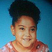 Image depicts Julie Cirella - a young African American girl with her black hair pulled back into a high puffy ponytail facing the camera with a big warm smile.