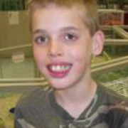 Image depicts Kyle Dutter - a young Caucasian boy with short blonde hair facing the camera smiling widely.