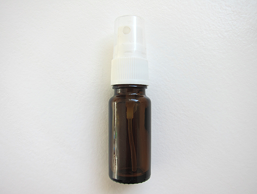 Small spray bottle, brown glass with white closure and transparent lid.