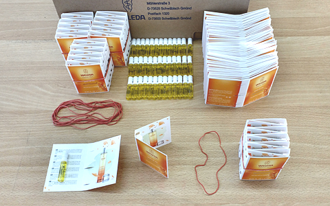 A desk with bunches of finished, counted, and bundled up sample packaging. In the front an open sample packaging with the sample visible inside.