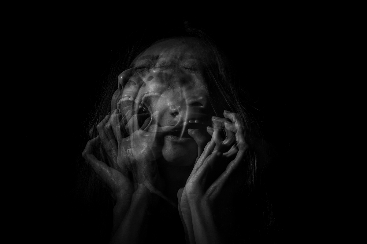 Schwarz-weiß Bild mit komplett schwarzem Hintergrund und einer Menge an verschwommenen Bildern einer verstörten Person, die schreit, übereinandergelagert.