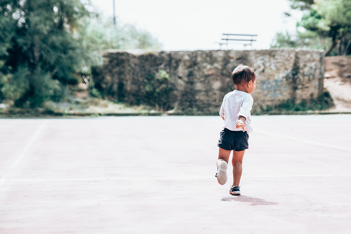 Young dark skinned child running away from the camera.